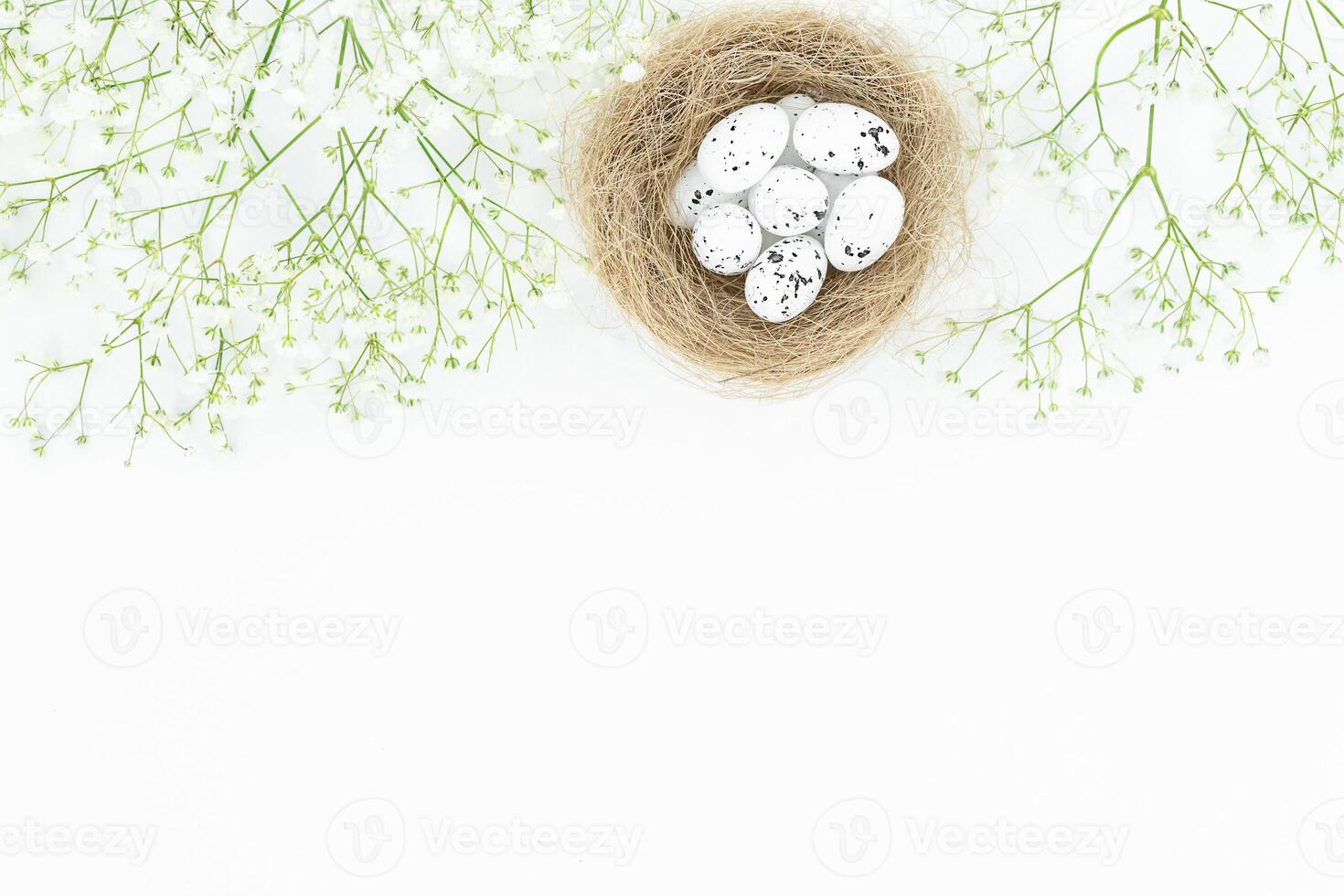 Easter light background with bird's nest, eggs and small white flowers on the top photo
