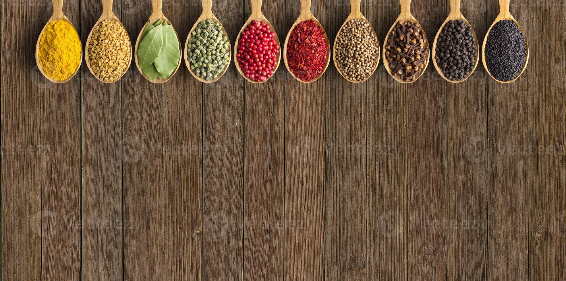 Various spices and herbs in wooden spoons. Condiments on vintage table with empty space for text or label. photo