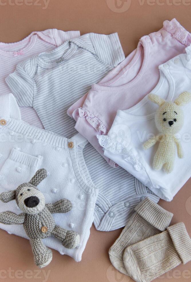 Set of pink clothes and accessories for newborn baby. Knitted toys rabbit and dog, romper, socks and handband photo