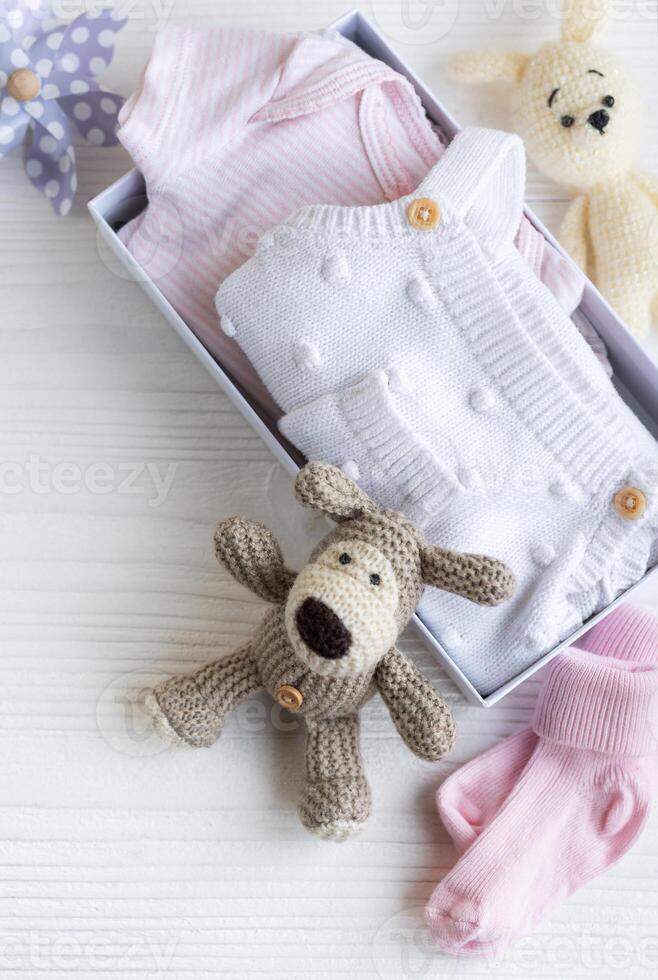 Baby clothes, knitted toys, socks in box. photo