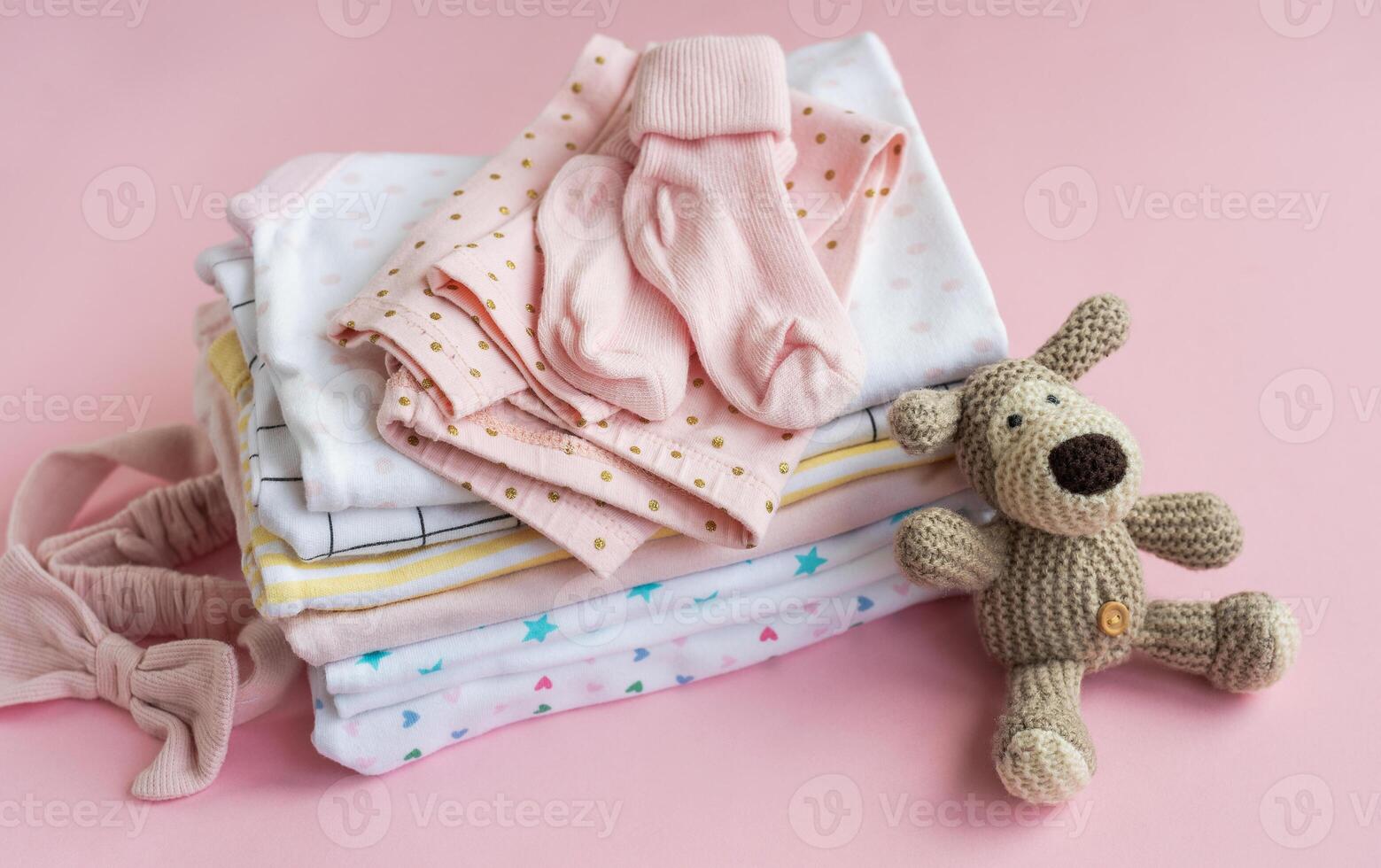 Baby crocketed toy of dog next to a stack rompers for kids photo