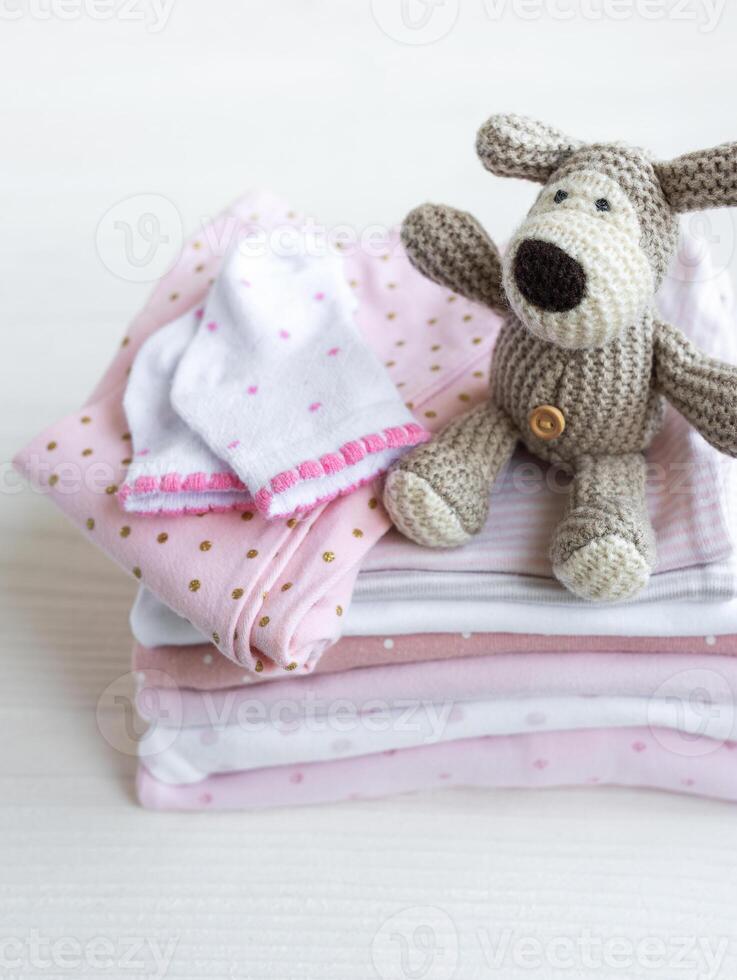 Stack of baby clothes, socks and knitted toy photo