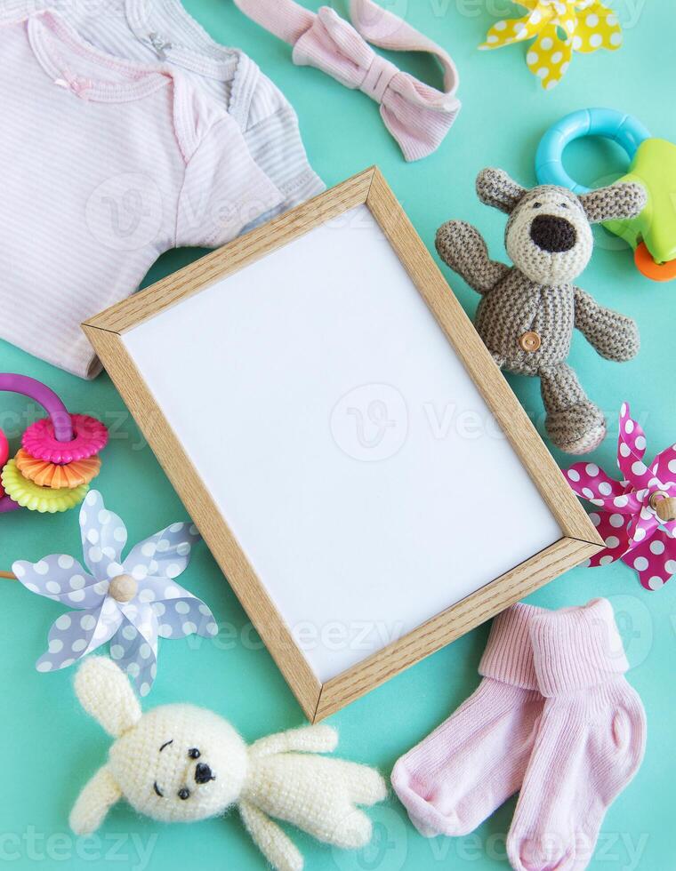 Baby garment and accessories and empty frame mockup. photo