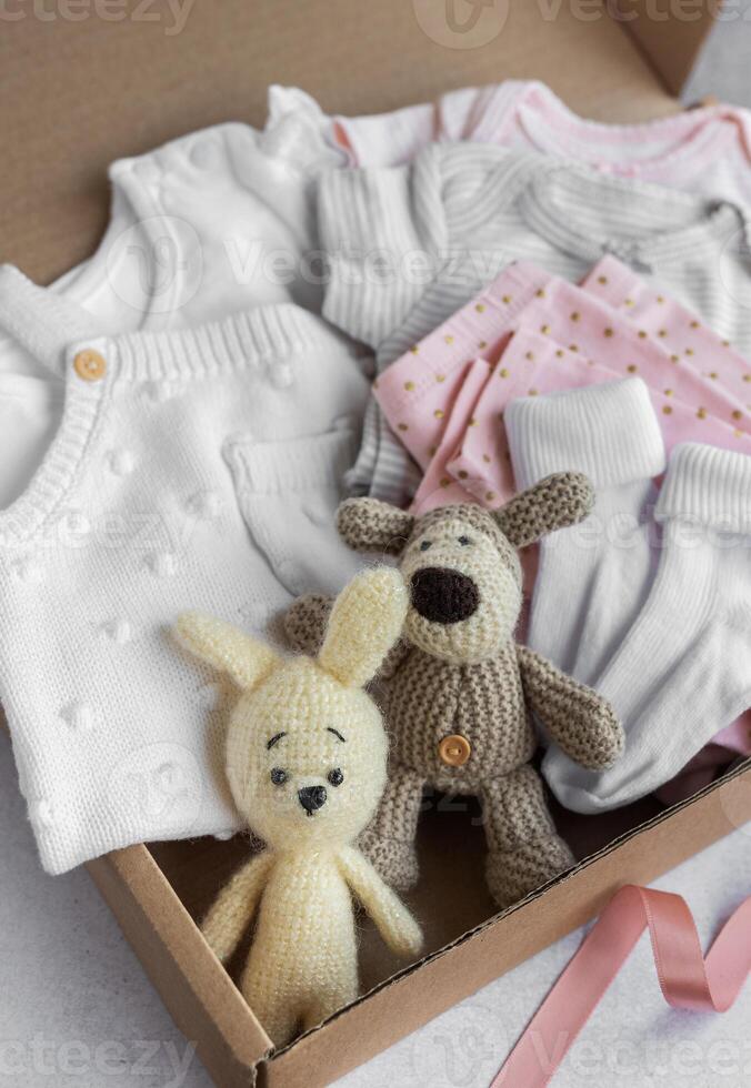 Baby and child clothes and knitted toys in carton box. photo