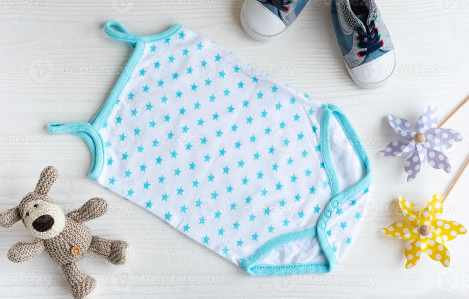 Blue romper with knittes toy dog, toy windmills and baby shoes. photo