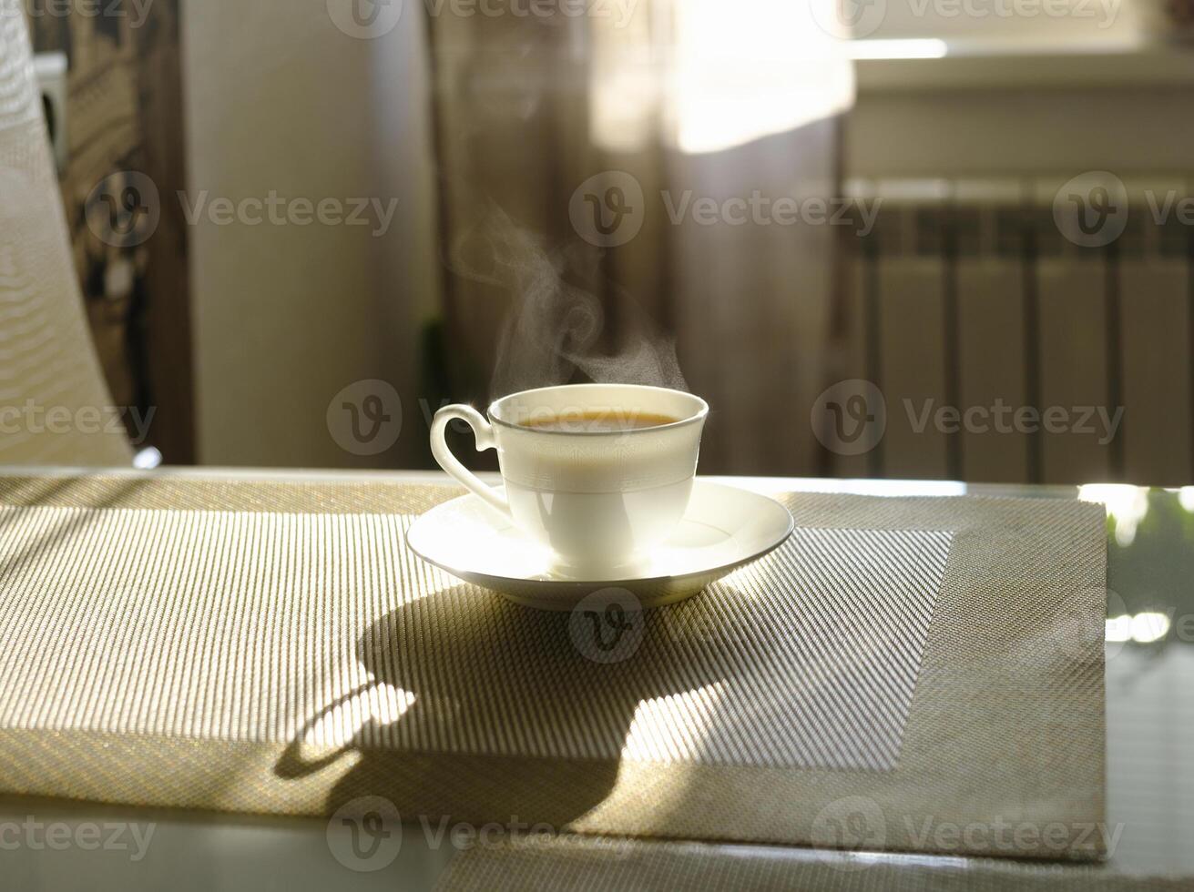 cup of hot steaming coffee on a sunny morning on the kitchen table photo