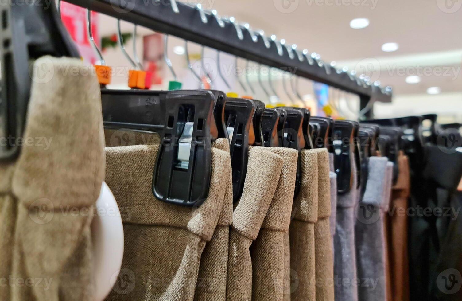 Rows of trousers in a clothing store hanging neatly on hangers. photo