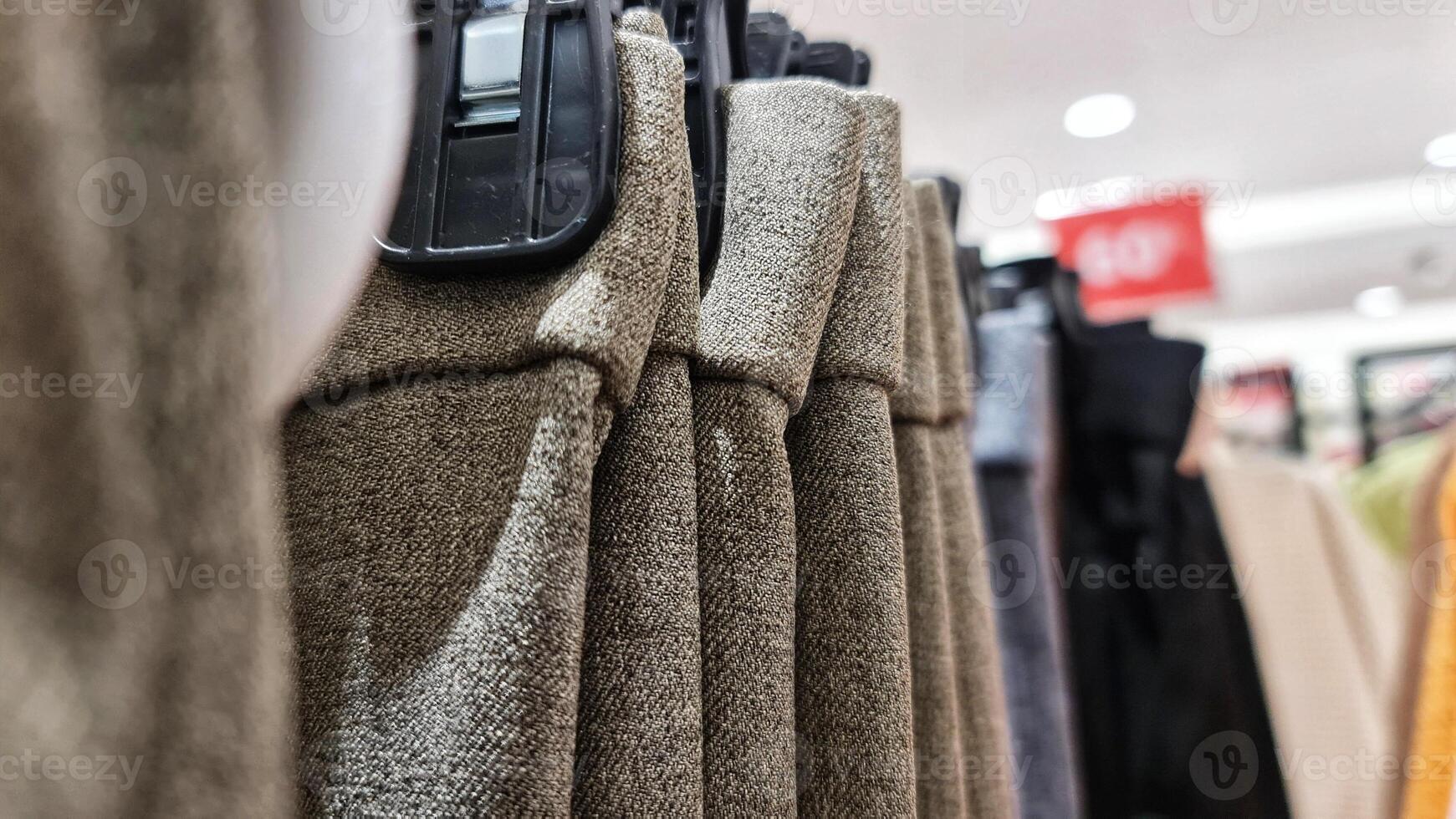 Rows of trousers in a clothing store hanging neatly on hangers. photo