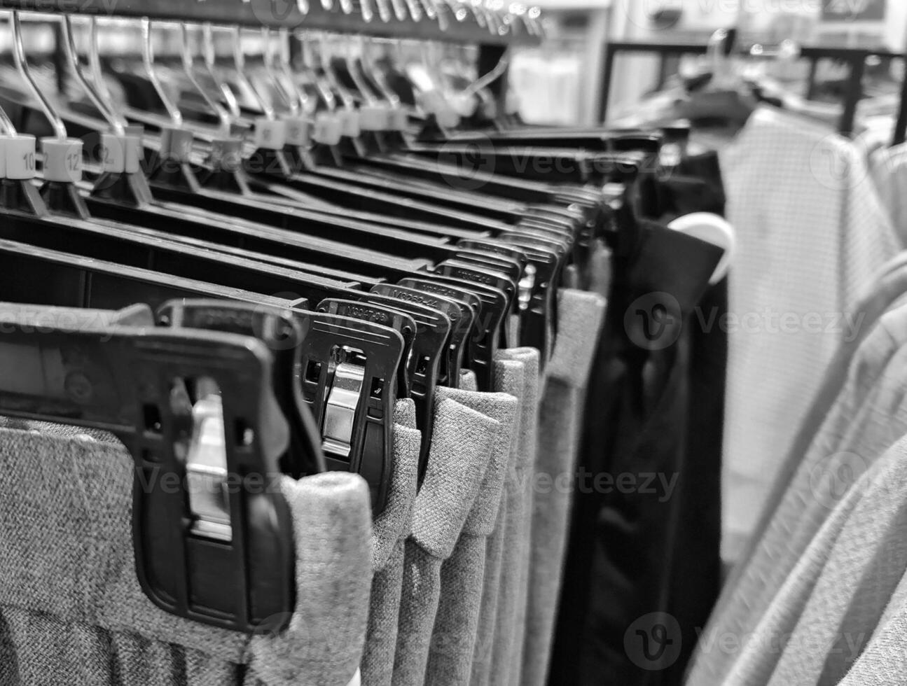 Rows of trousers in a clothing store hanging neatly on hangers. photo