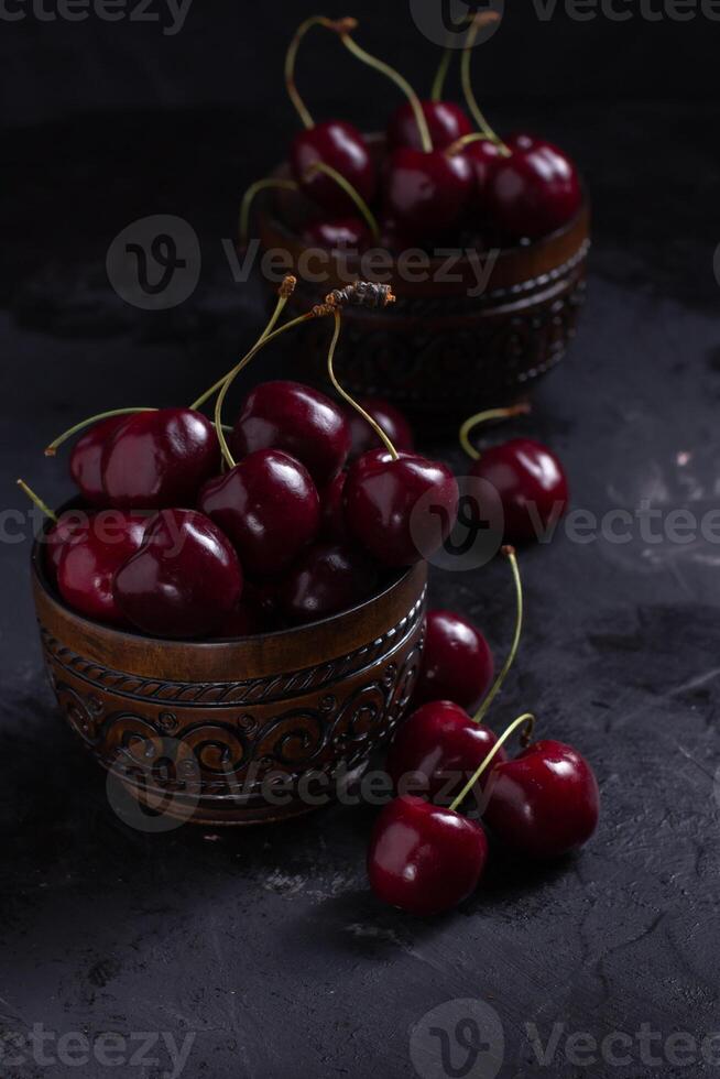 Organic juicy cherry in a bowl on dark background. Close-up photo, low key photo