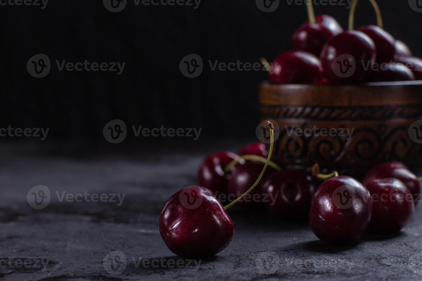 Organic juicy cherry in a bowl on dark background. Close-up photo, low key, selective focus photo