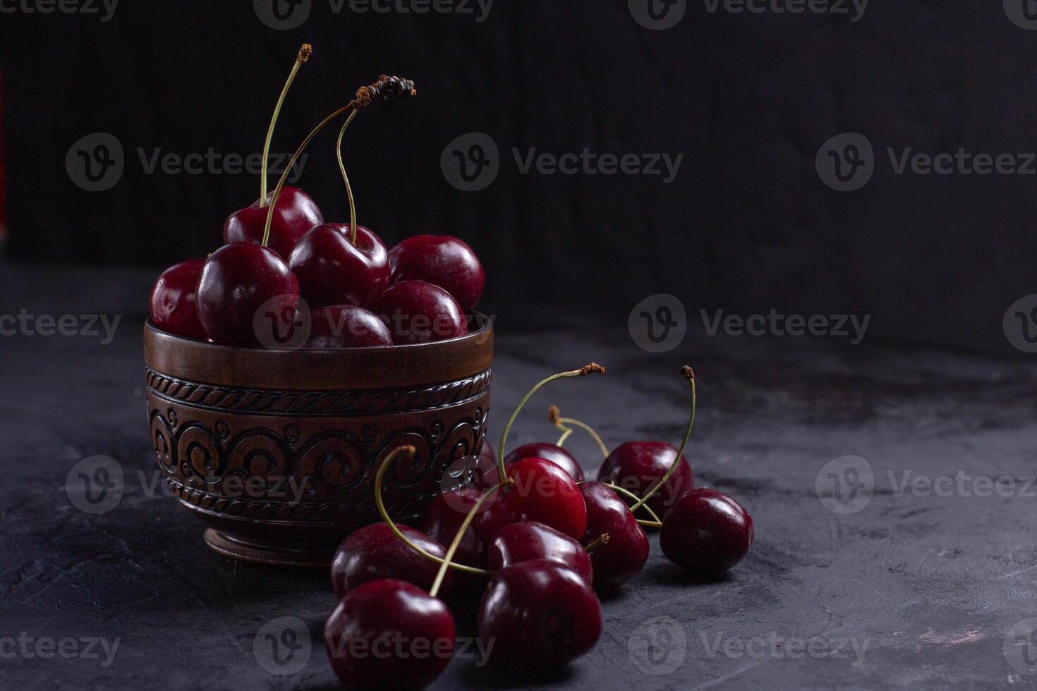 Organic juicy cherry in a bowl on dark background. Close-up photo, low key photo