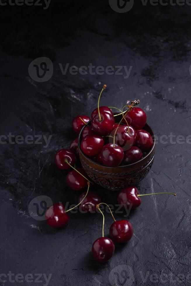 Organic juicy cherry in a bowl on dark background. Close-up photo, low key photo