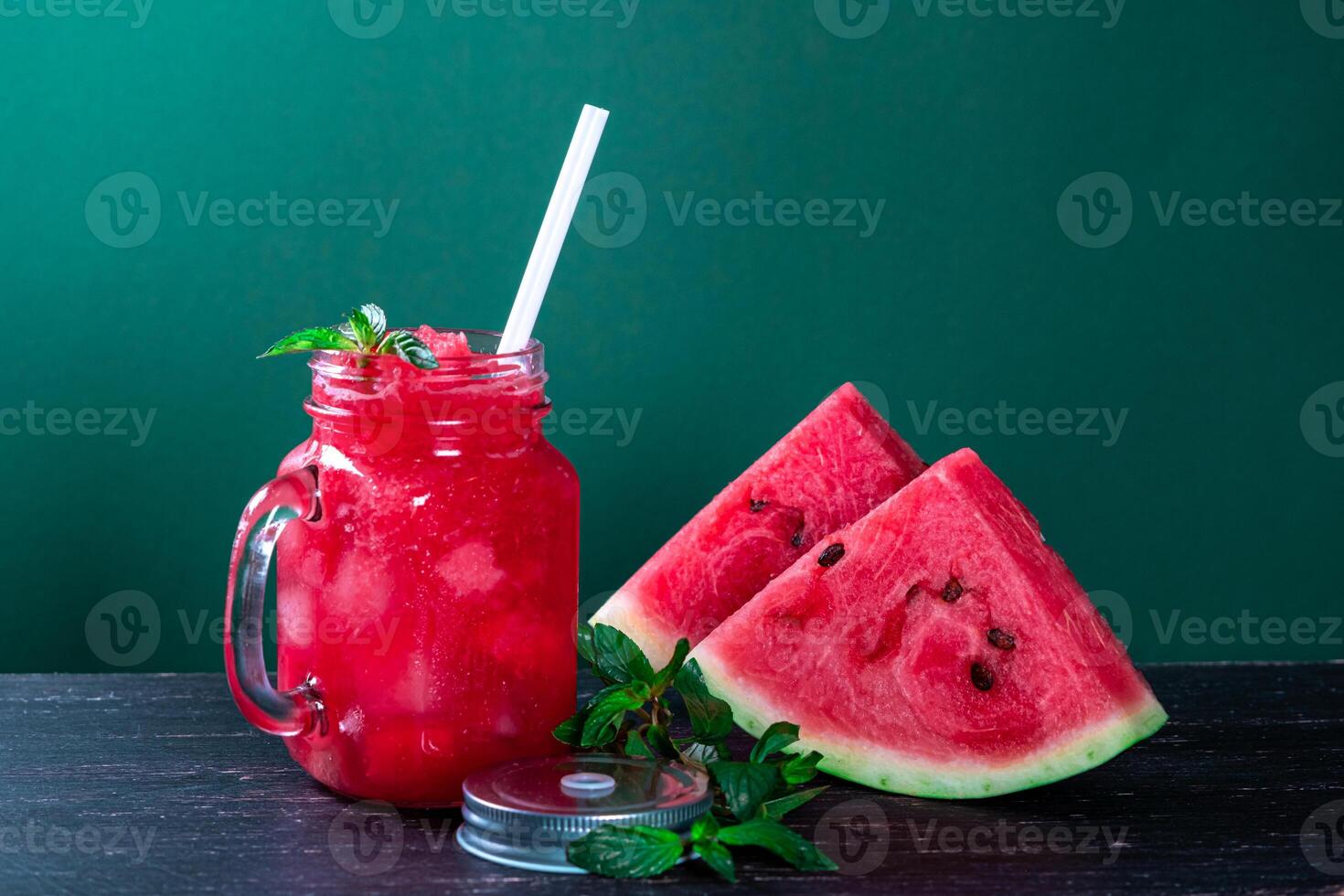 Cold watermelon smoothie and pieces of refreshment watermelon on dark background. Fresh summer drink. photo