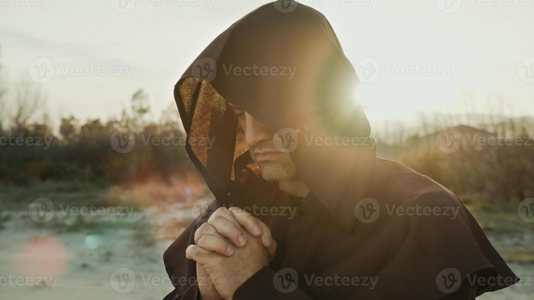 Religious Monk Wears His Hood And Prays In Nature At Sunset photo