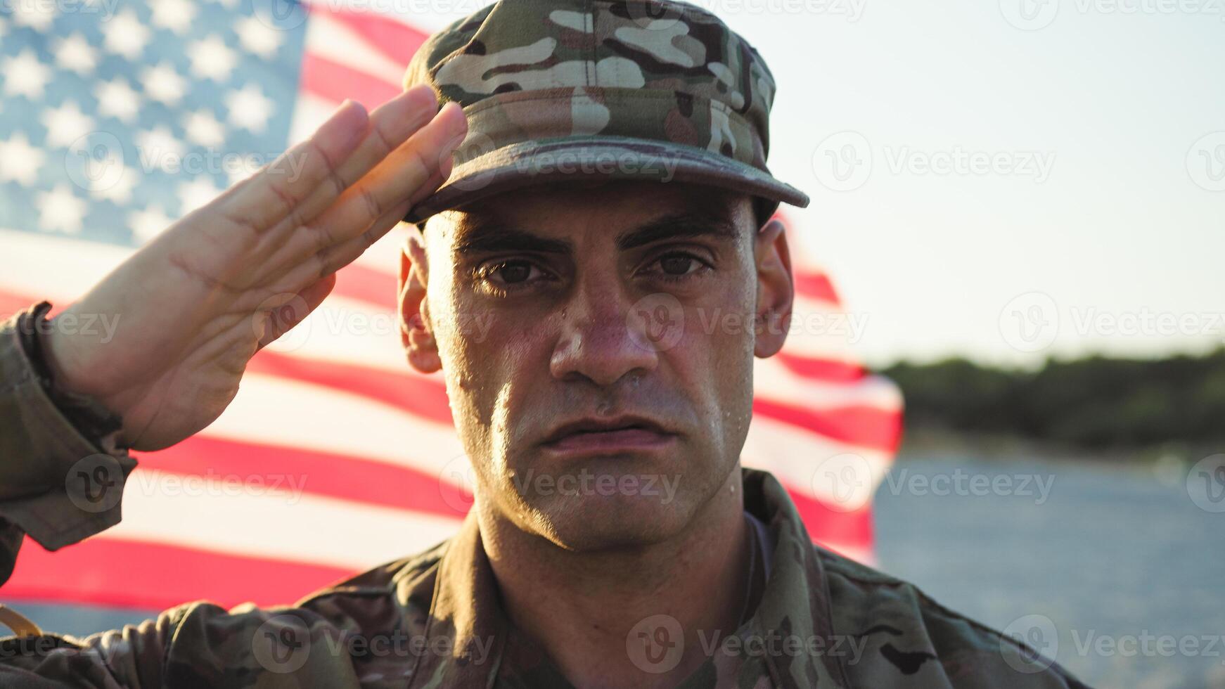 Soldier in uniform standing at attention next to the American flag photo