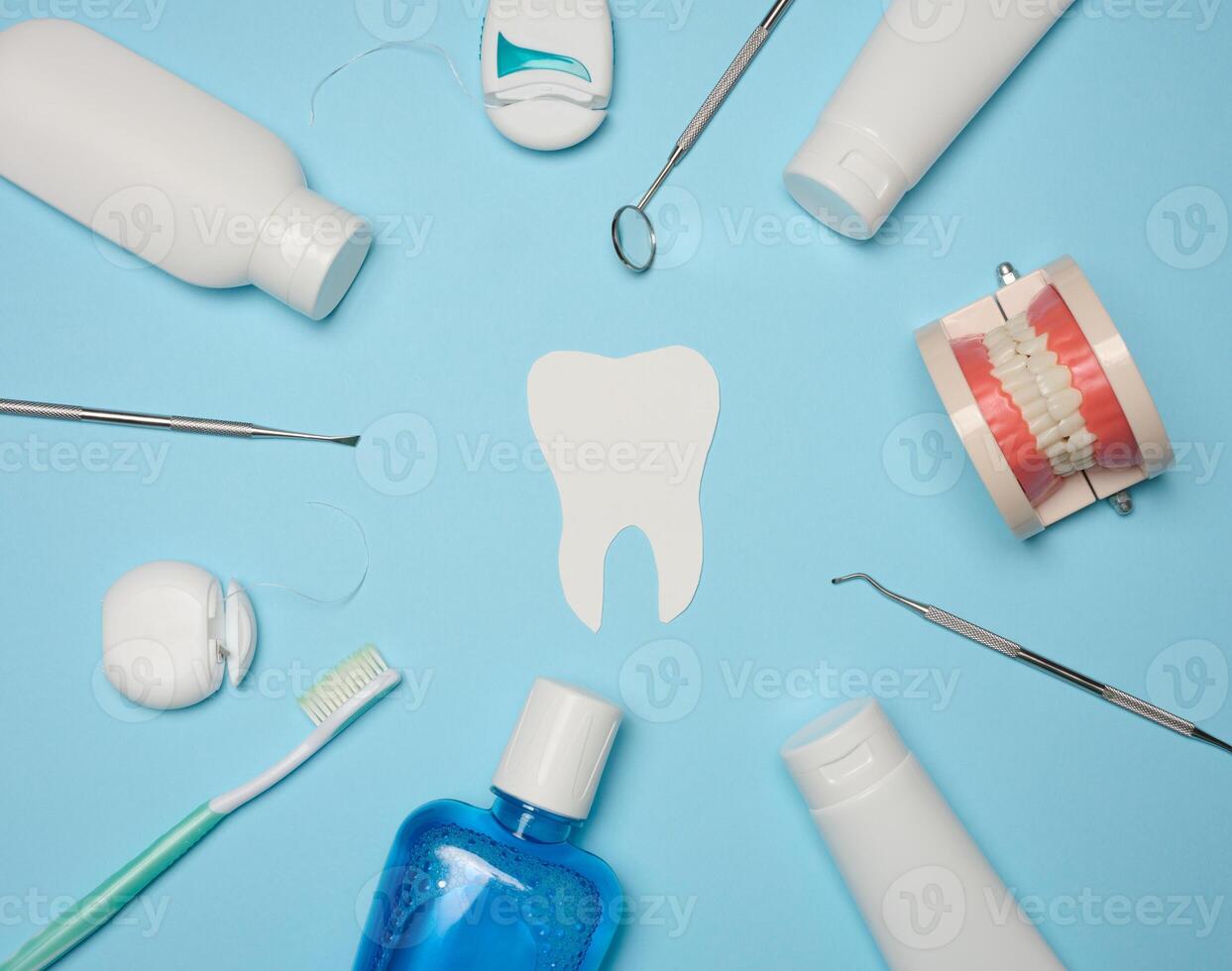 Mouthwash, toothpaste tube, dental floss and medical mirror on a blue background, oral hygiene. Top view photo