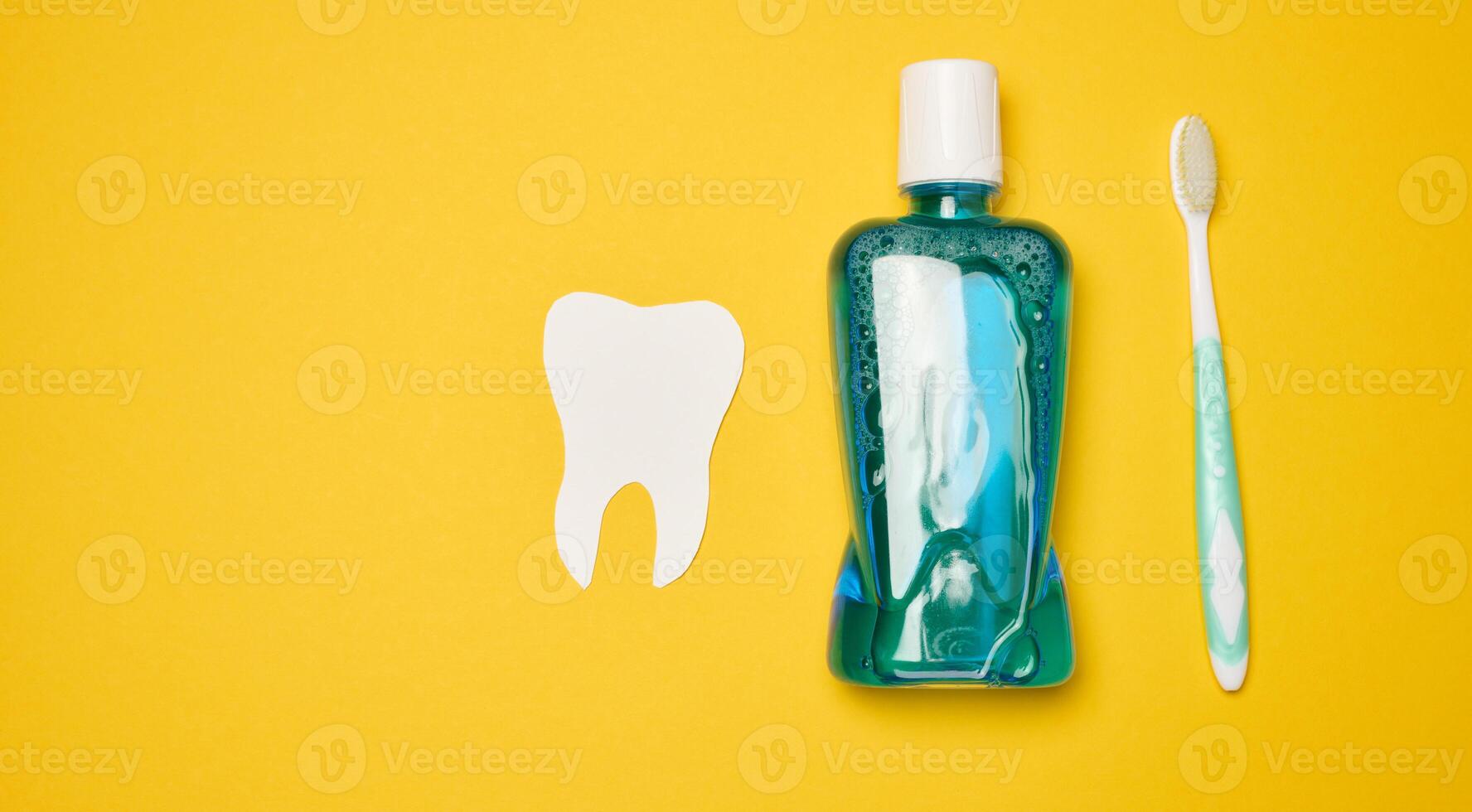 Mouthwash and toothbrush on yellow background, top view photo