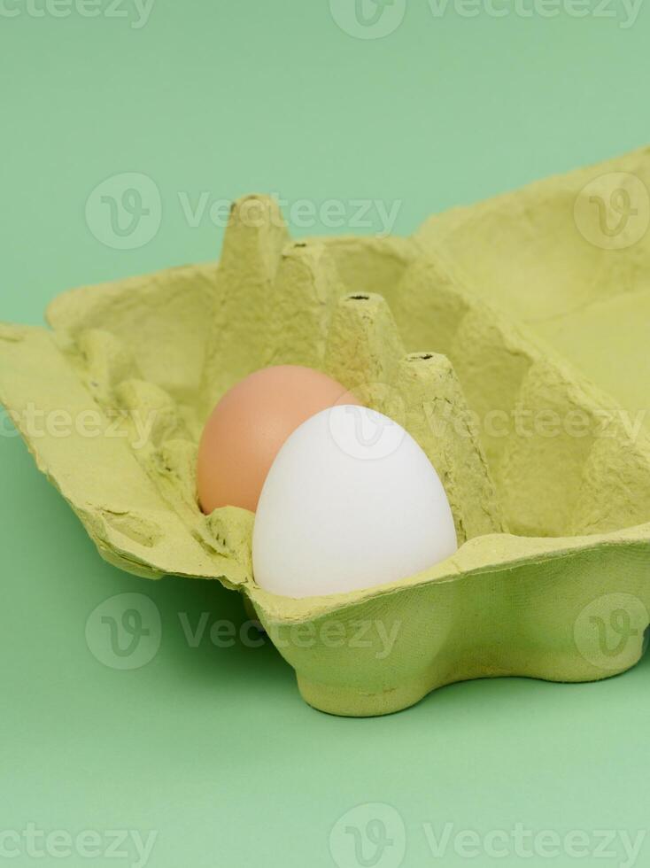 dos pollo huevos en un papel caja en un verde antecedentes foto