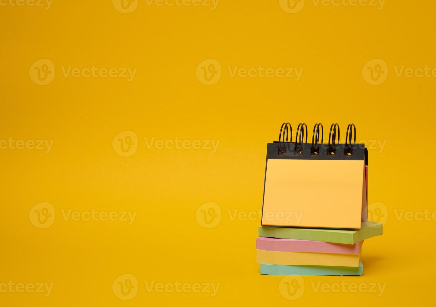 Stack of paper multi-colored stickers on a yellow background photo
