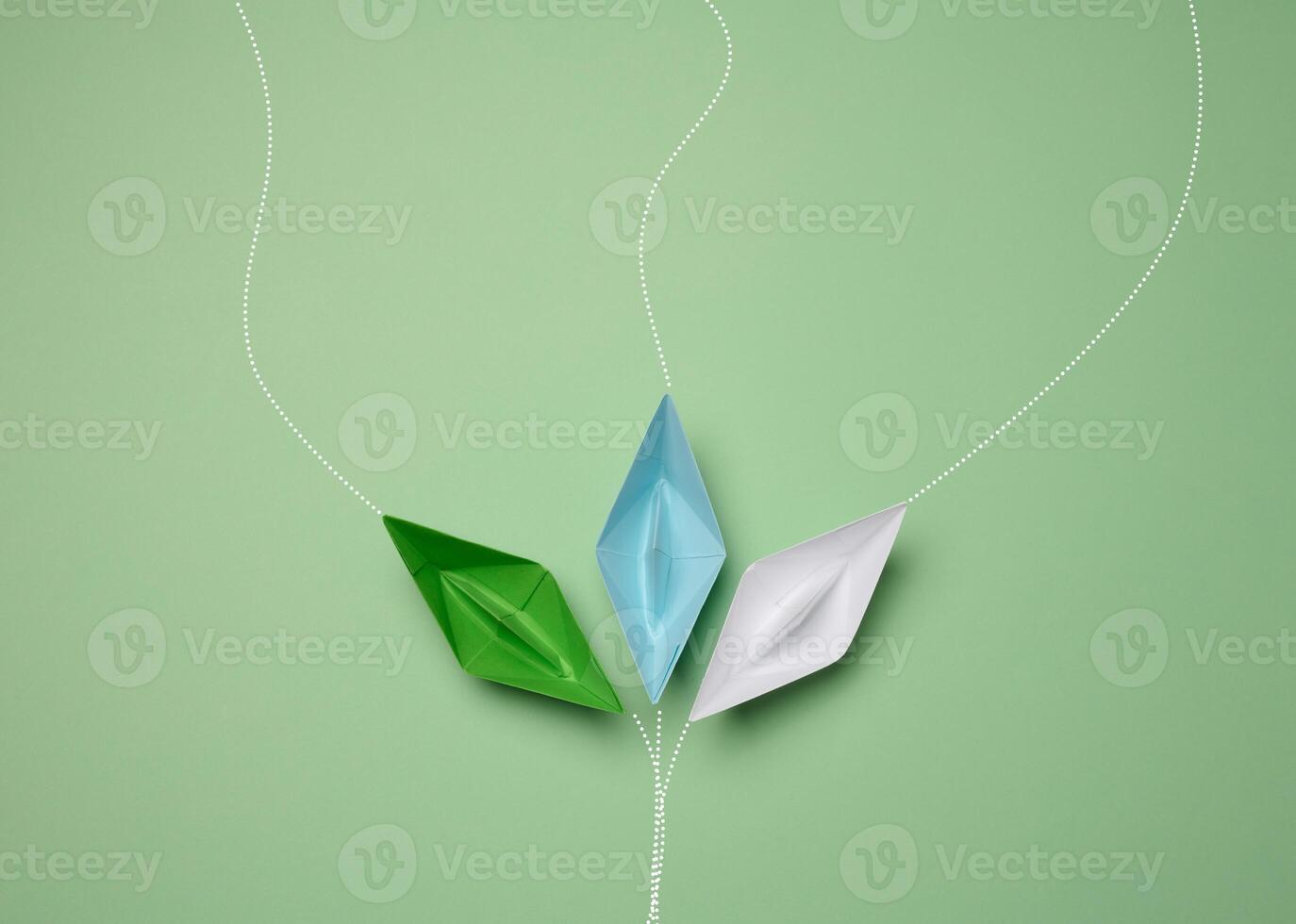 Paper boats on a green background with paths of movement, representing the concept of individuality. photo