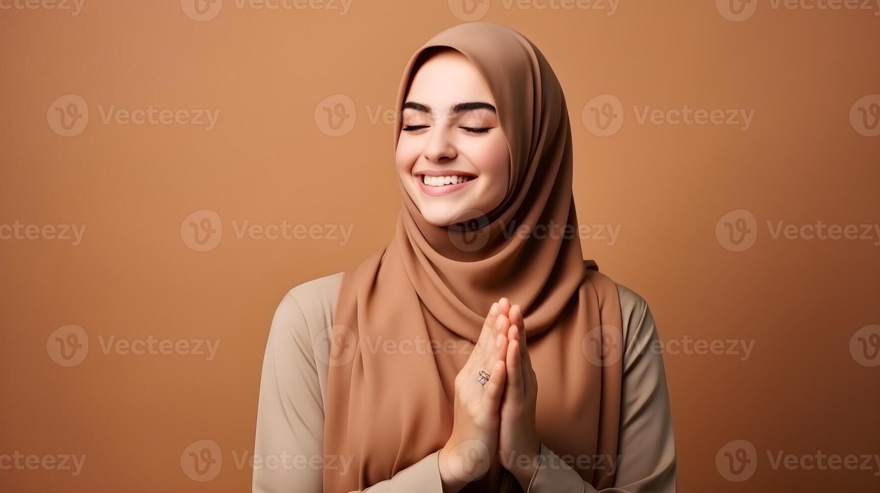 European woman wearing scarf is praying and smiling on brown background photo