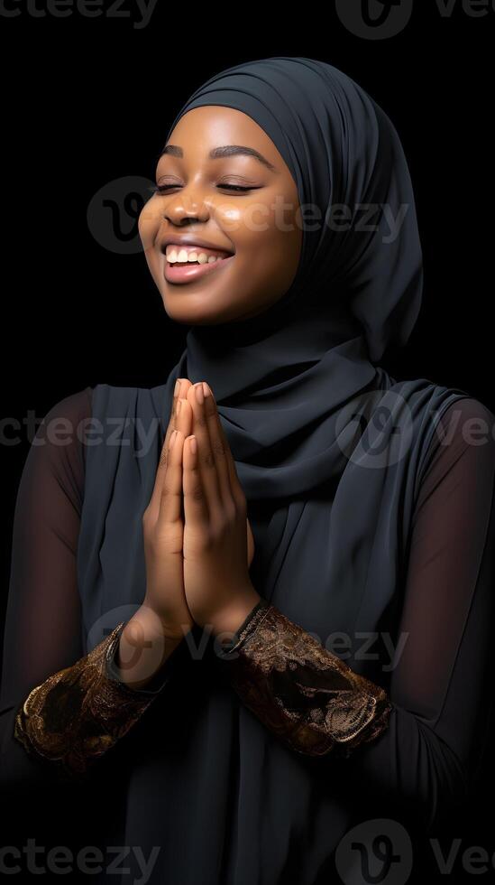 African woman wearing scarf is praying and smiling on black background photo