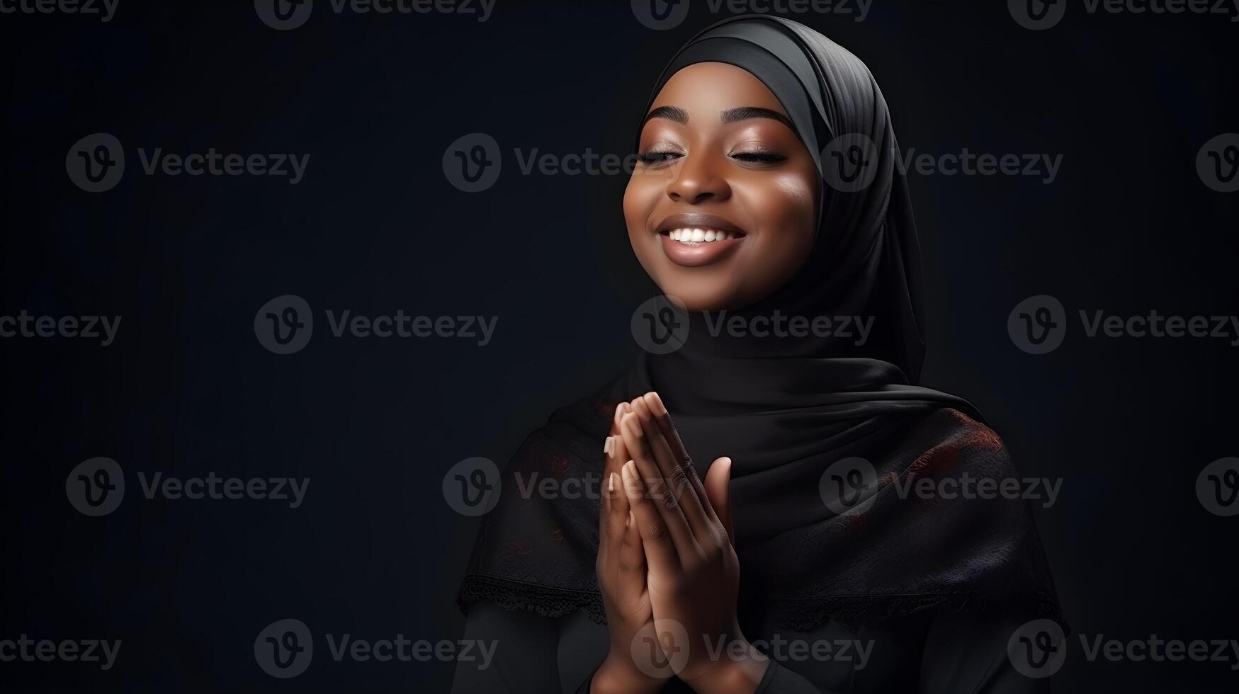 African woman wearing scarf is praying and smiling on black background photo