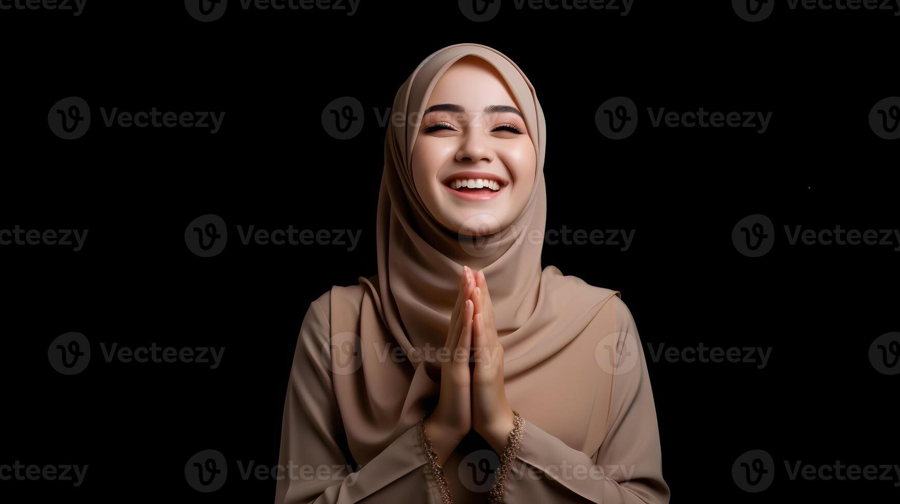 Arabic woman wearing scarf is praying and smiling on black background photo