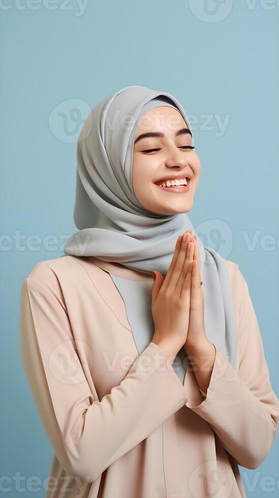 Southeast asian woman wearing scarf is praying and smiling on blue background photo