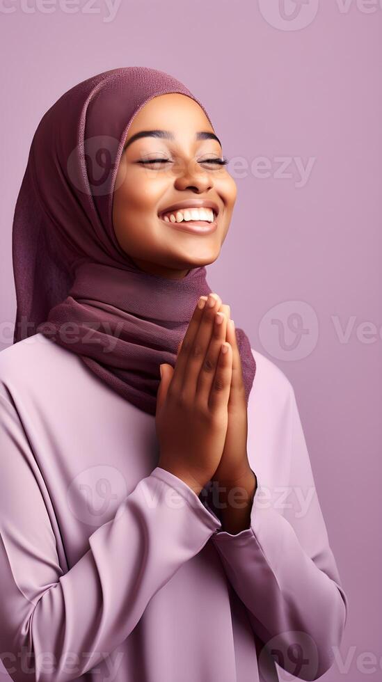 African woman wearing scarf is praying and smiling on purple background photo