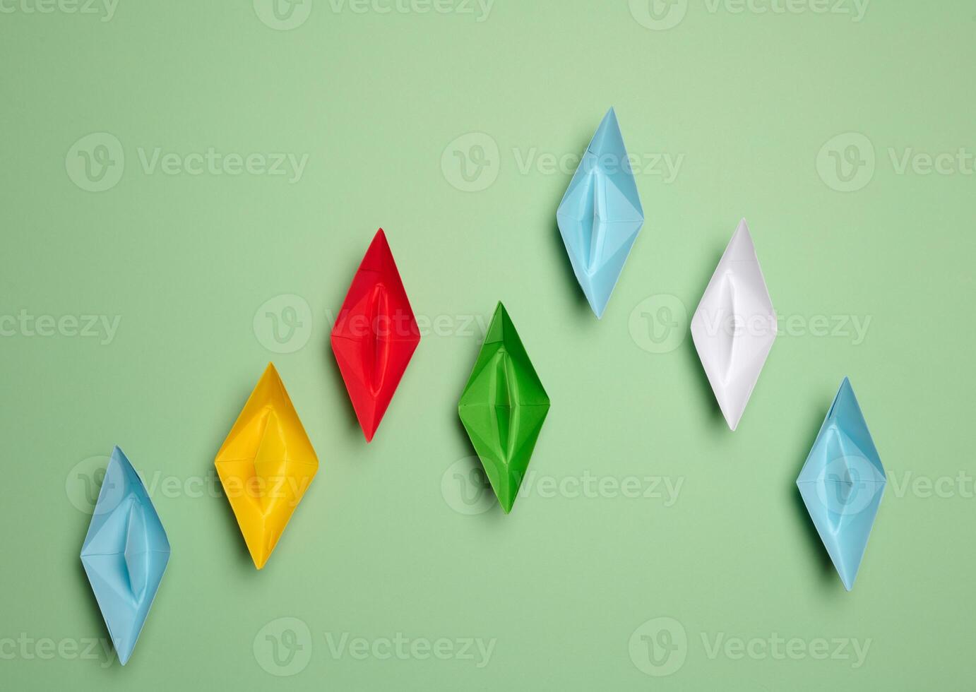 Multi-colored paper boats move forward, some of them rush forward. Concept of rivalry photo