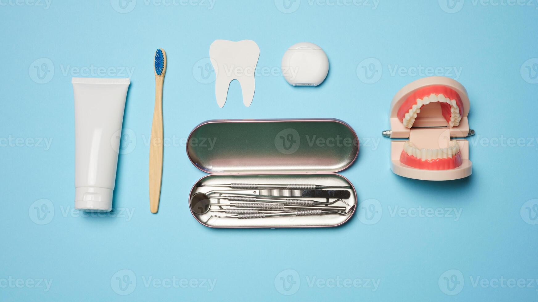 Mouthwash, toothpaste tube, dental floss and medical mirror on a blue background, oral hygiene. photo