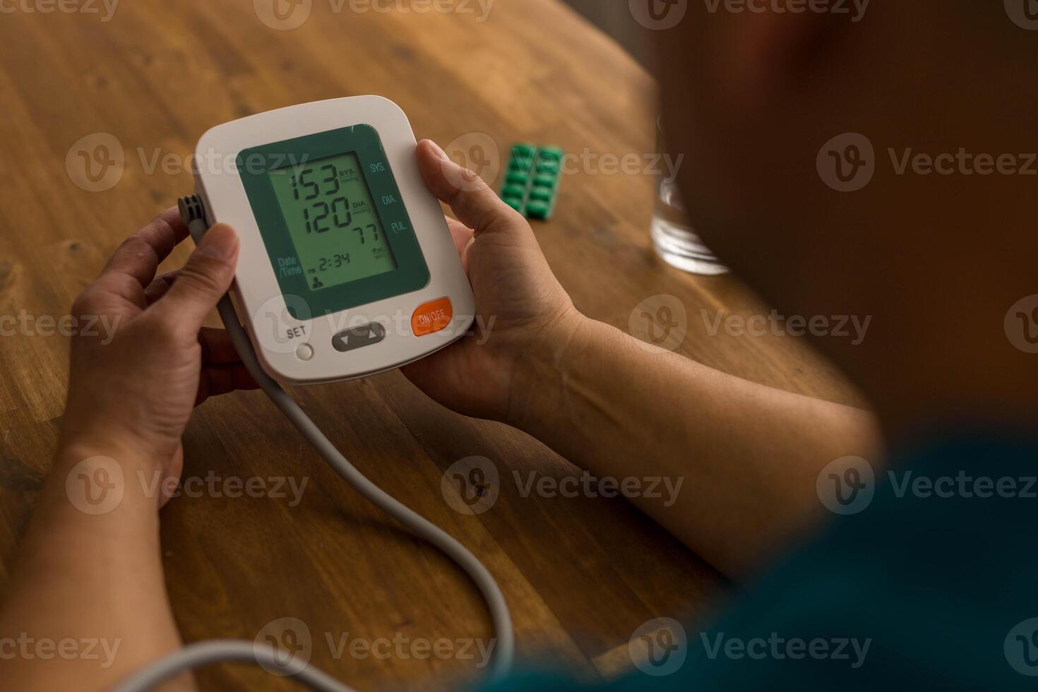 Seniory man checks blood pressure with monitor on upper arm in room photo