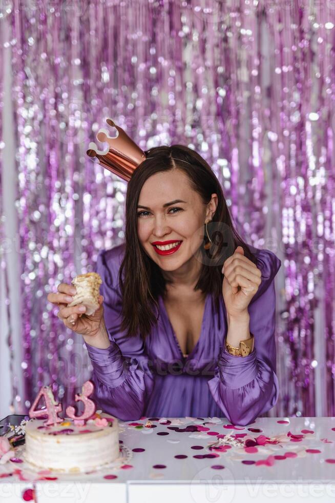 Woman celebrating her 43rd birthday. Bites the cake photo