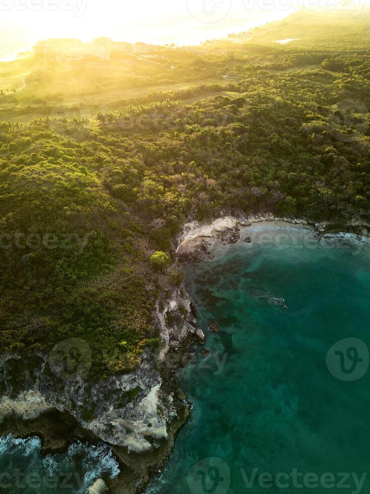 Aerial sunrise.Dark turquoise water with white foamy waves and green rocky shore photo