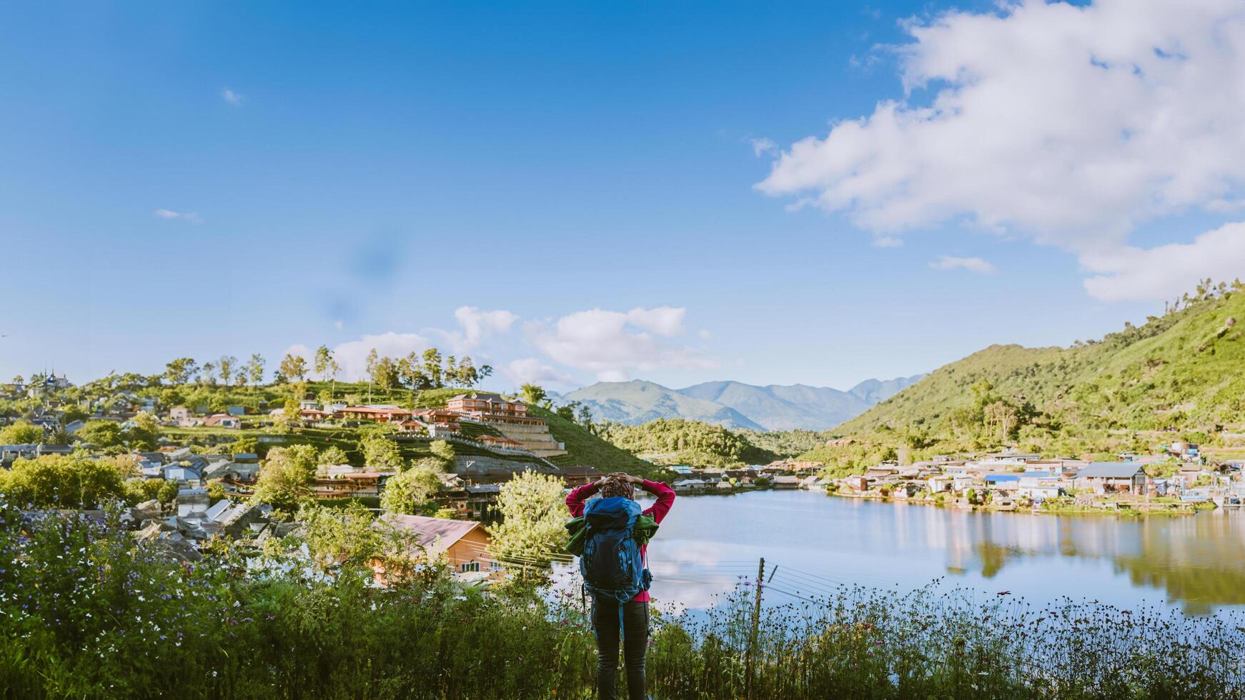 Girl with backpack stand looking forward on beautiful view in lake. Tourist traveler looking sunlight on mountains. Tea plantation in Mae Hong Son. photo