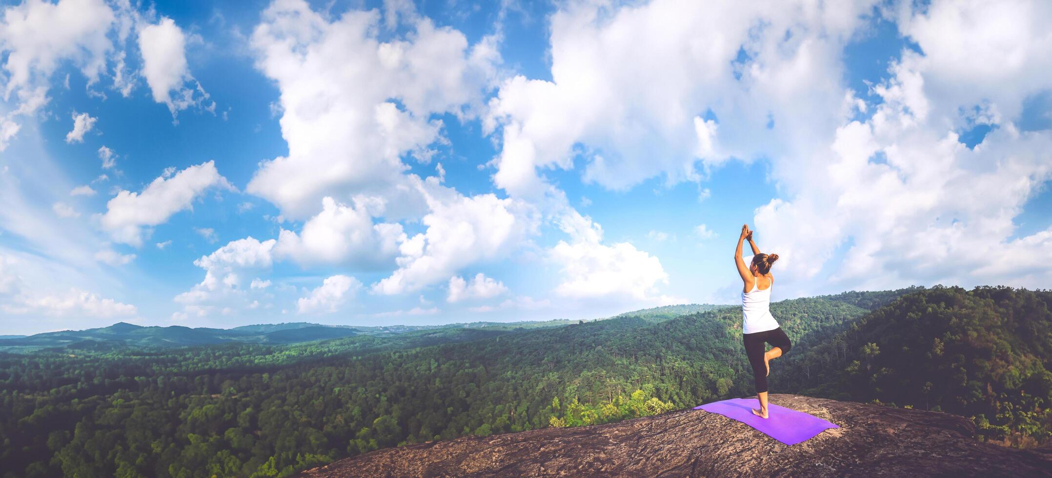 Asian women relax in the holiday. Play if yoga. On the Moutain rock cliff. Nature of mountain forests in Thailand photo