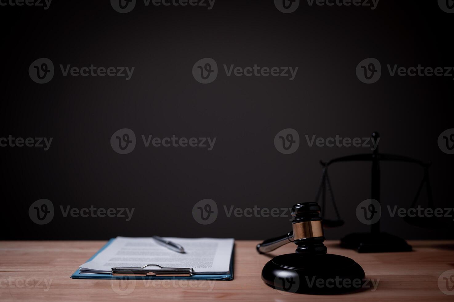 A judge's gavel sits on a desk next to a stack of papers. The scene is set in a courtroom, and the judge's gavel is a symbol of authority and order photo