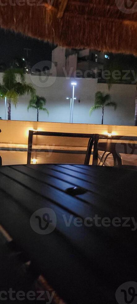image of dark table in garden with pool at night photo
