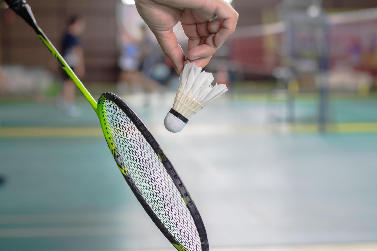 The badminton player holding a white shuttlecock and racket photo