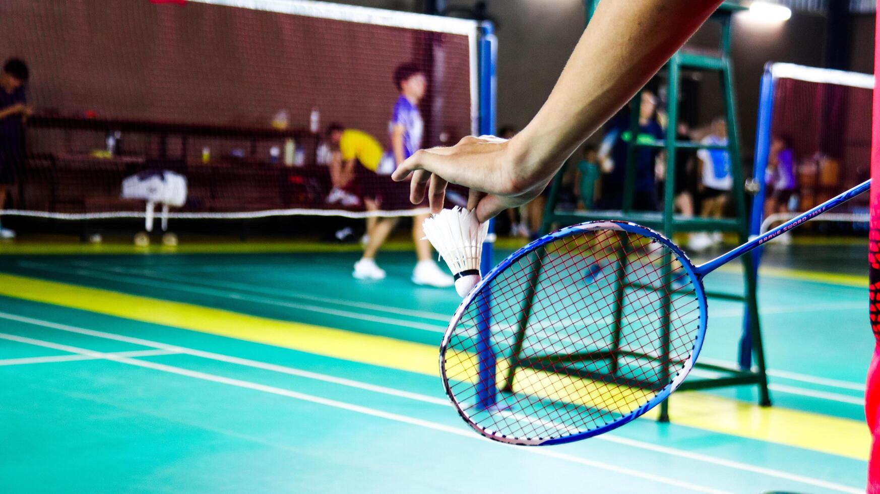 The badminton player holding a white shuttlecock and racket photo