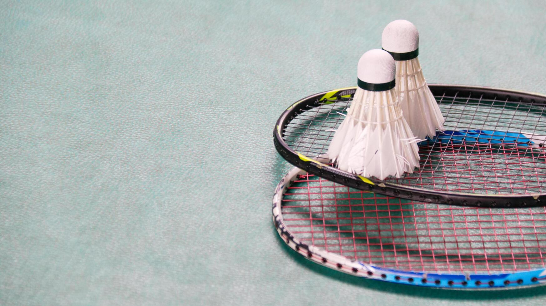 White badminton shuttlecocks and badminton rackets on green floor indoor badminton court soft and selective focus on shuttlecocks and the rackets photo