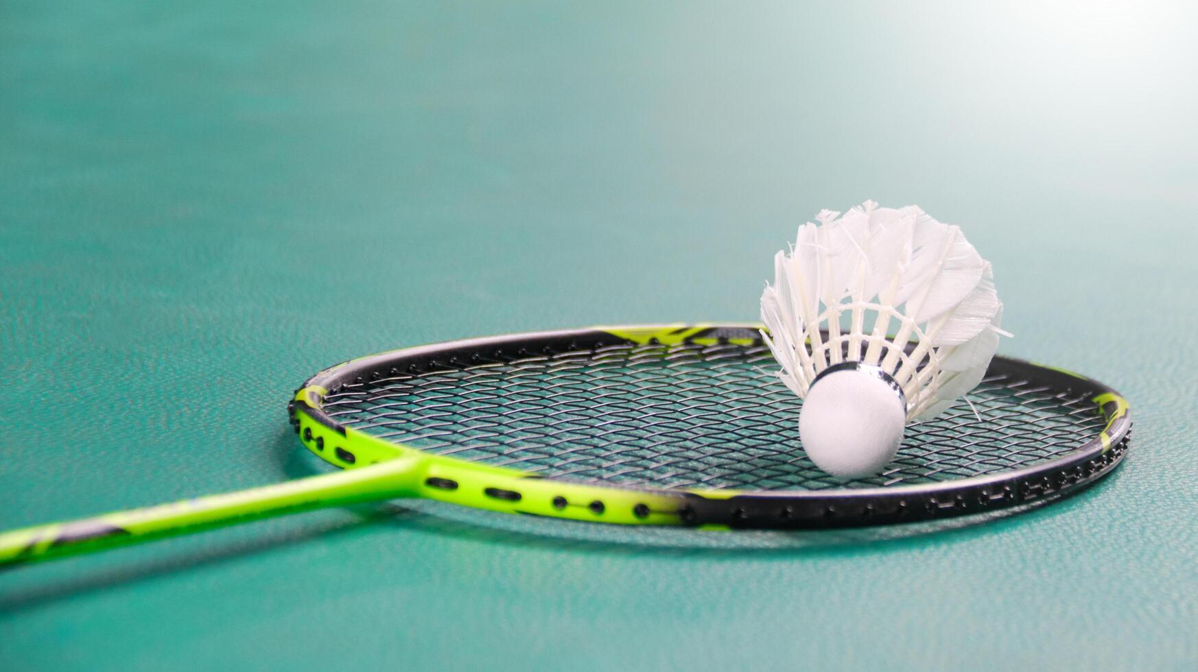 White badminton shuttlecocks and badminton rackets on green floor indoor badminton court soft and selective focus on shuttlecocks and the rackets photo