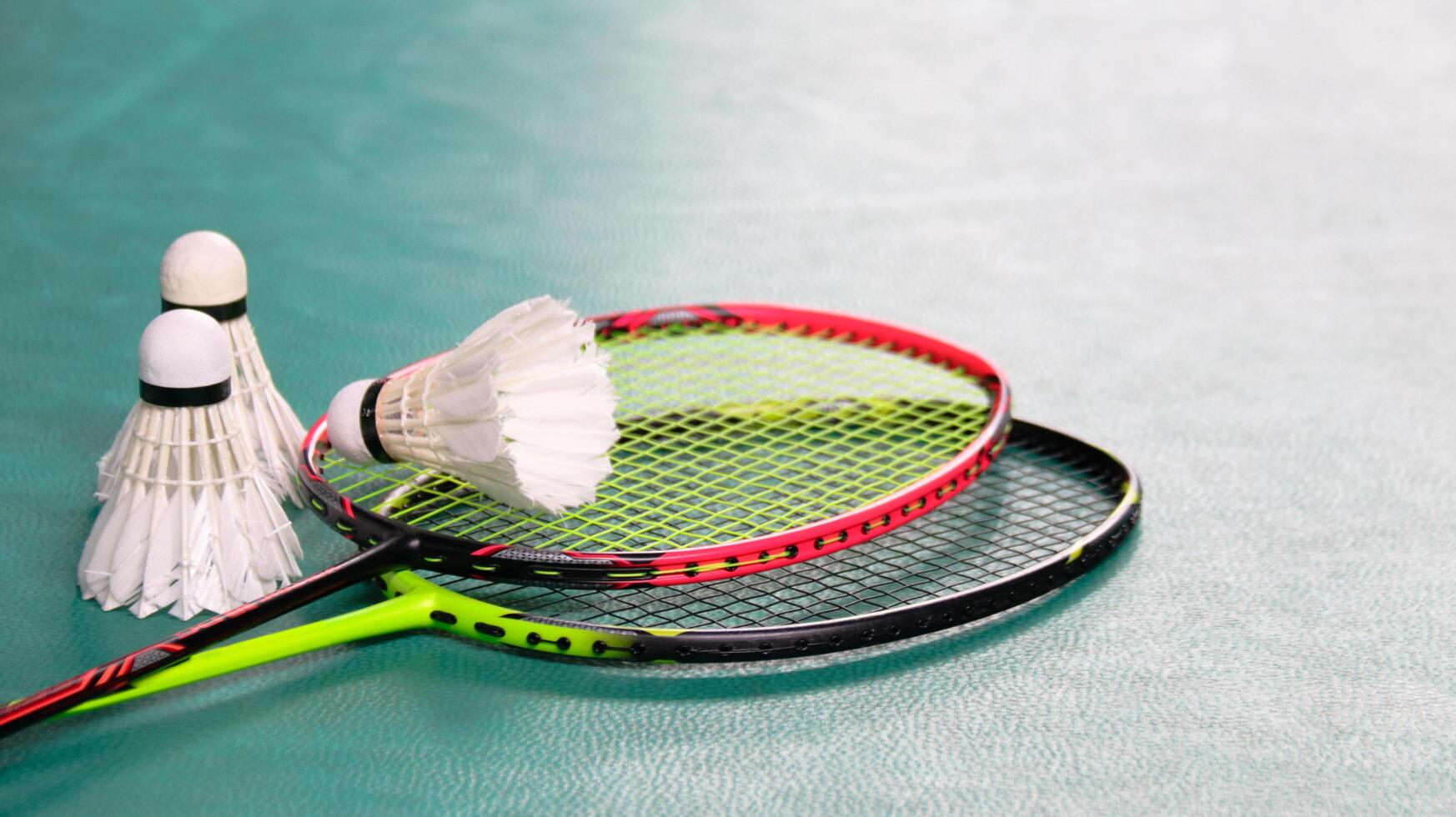 White badminton shuttlecocks and badminton rackets on green floor indoor badminton court soft and selective focus on shuttlecocks and the rackets photo