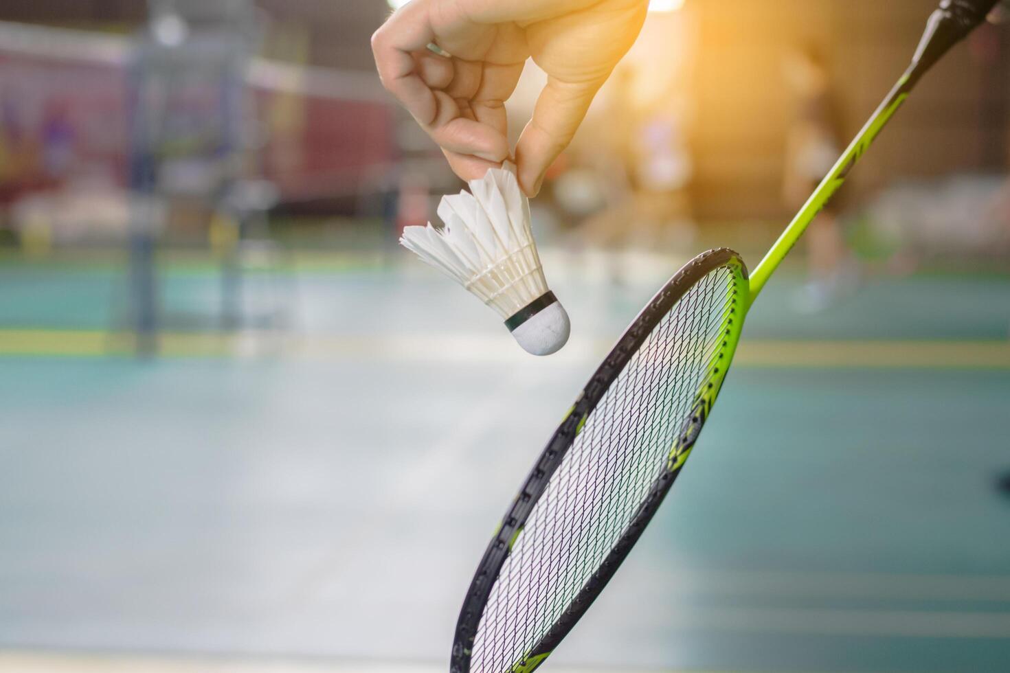 The badminton player holding a white shuttlecock and racket photo