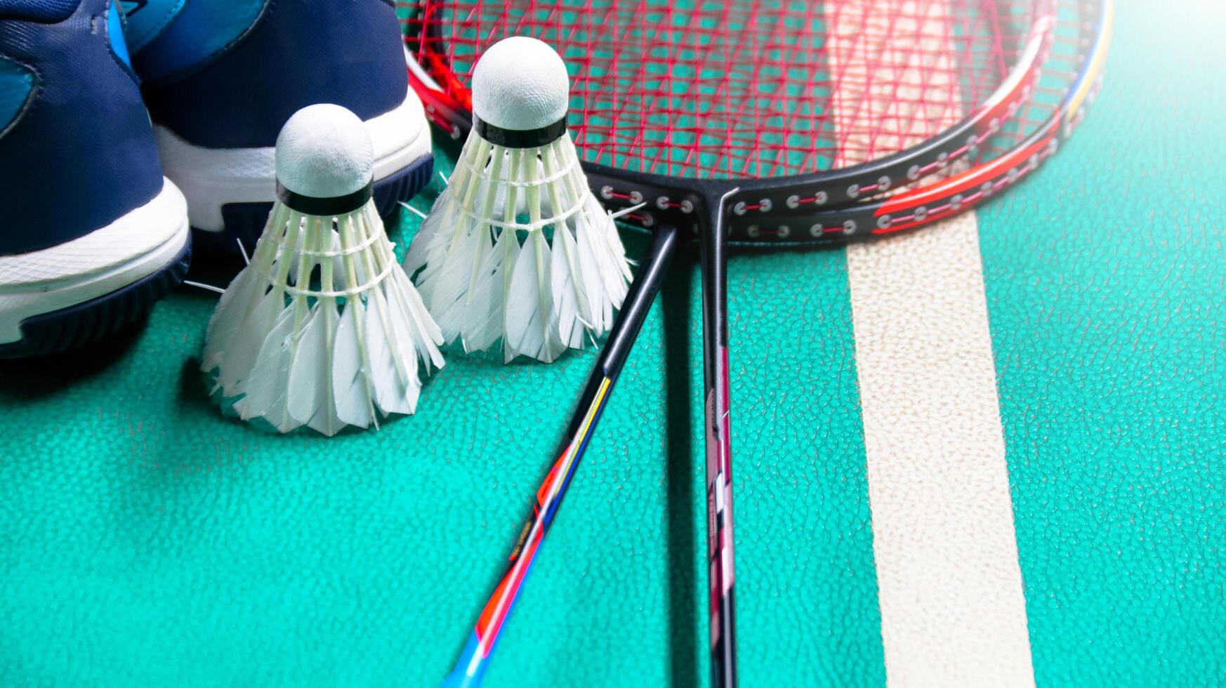 White badminton shuttlecocks and badminton rackets on green floor indoor badminton court soft and selective focus on shuttlecocks and the rackets photo