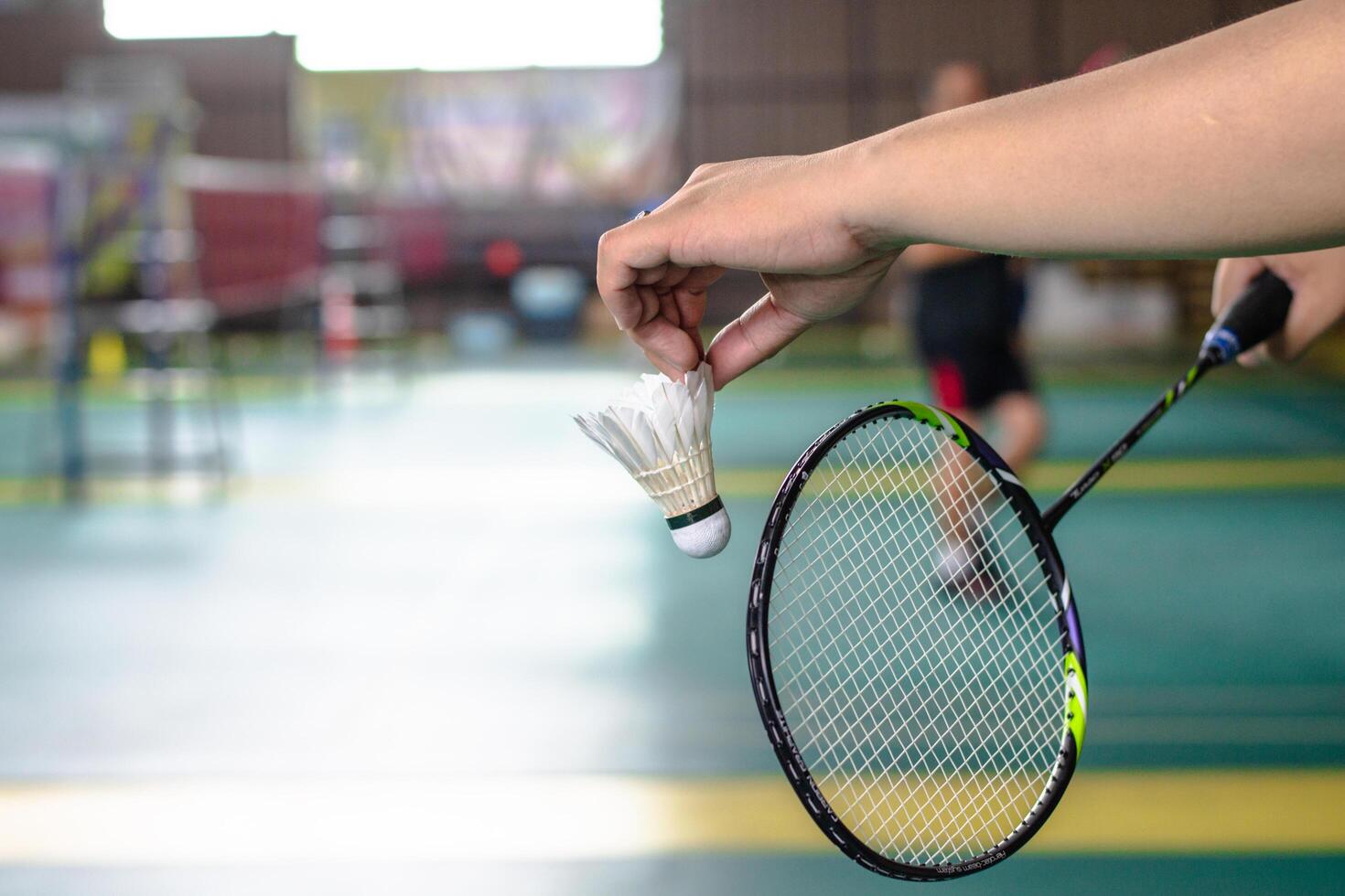 The badminton player holding a white shuttlecock and racket photo