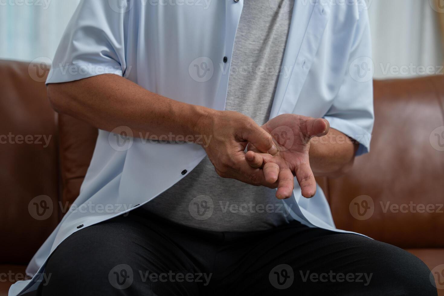 Elderly Asian male patients suffer from numbing pain in hands from rheumatoid arthritis. Senior men massage his hand with wrist pain. Concept of joint pain, rheumatoid arthritis, and hand problems. photo