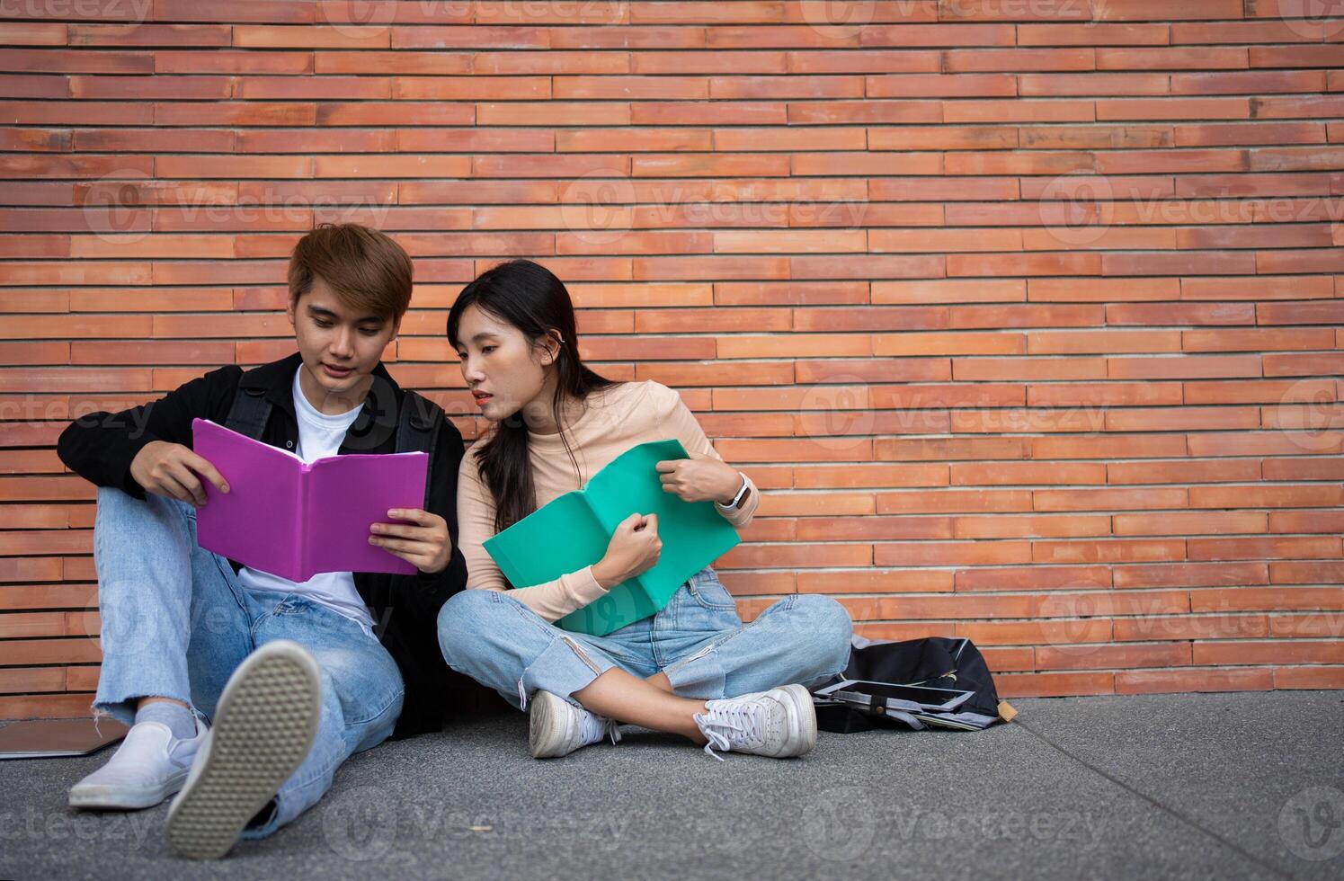 grupo de joven interracial diverso Universidad estudiantes leyendo libro de texto y sentado fuera de un salón de clases debajo un edificio, atractivo en un discusión juntos, Universidad instalaciones, disfrutando instalaciones recreación. foto